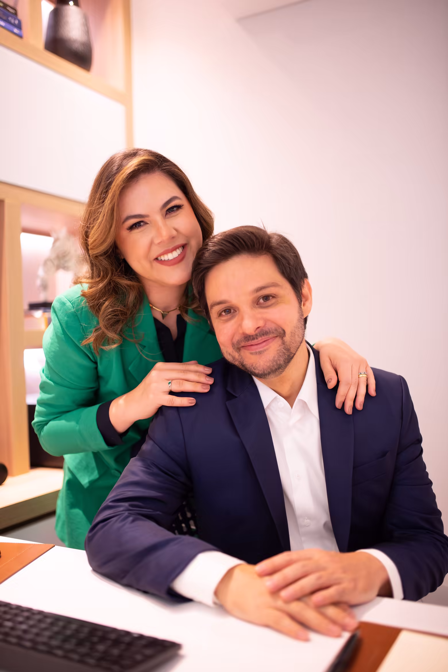 Dr. Osório Lara sentado à mesa do consultório e Dra. Aline Soares em pé ao lado dele, com a mão em seu ombro.